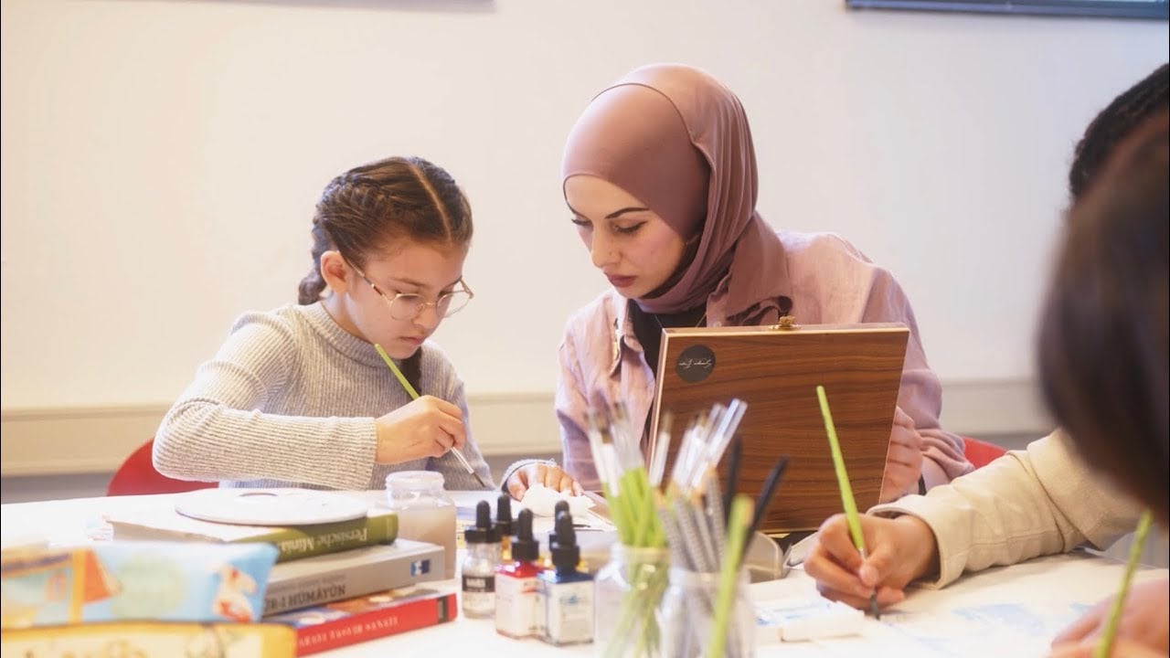 Juf Sümeyra helping a child paint during a miniature-art workshop supported by YTB